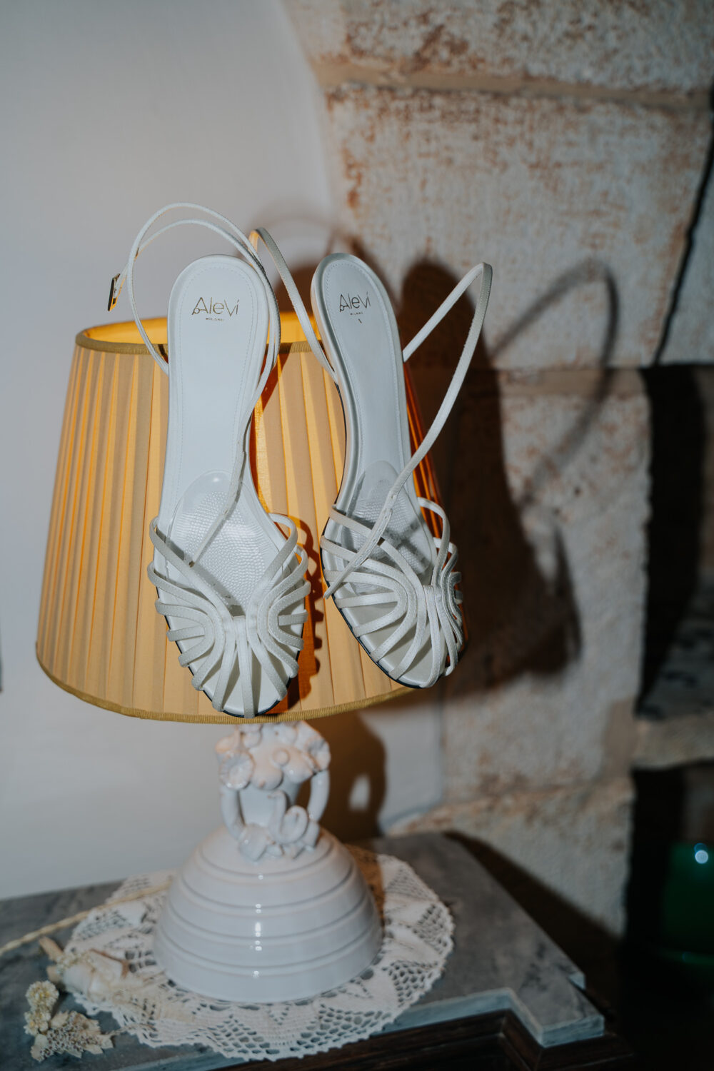 Masseria San Paolo Grande Wedding: Yasemin & Omer's Ostuni Celebration 6 Bride's wedding shoes displayed on a bedside lamp before the ceremony