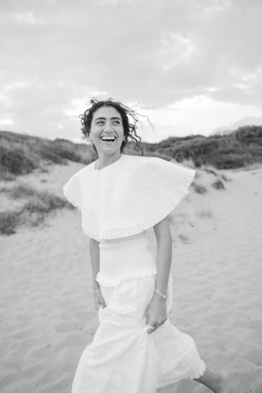 Masseria San Paolo Grande Wedding: Yasemin & Omer's Ostuni Celebration 28 Bride laughing on the beach dunes near Ostuni a Mare