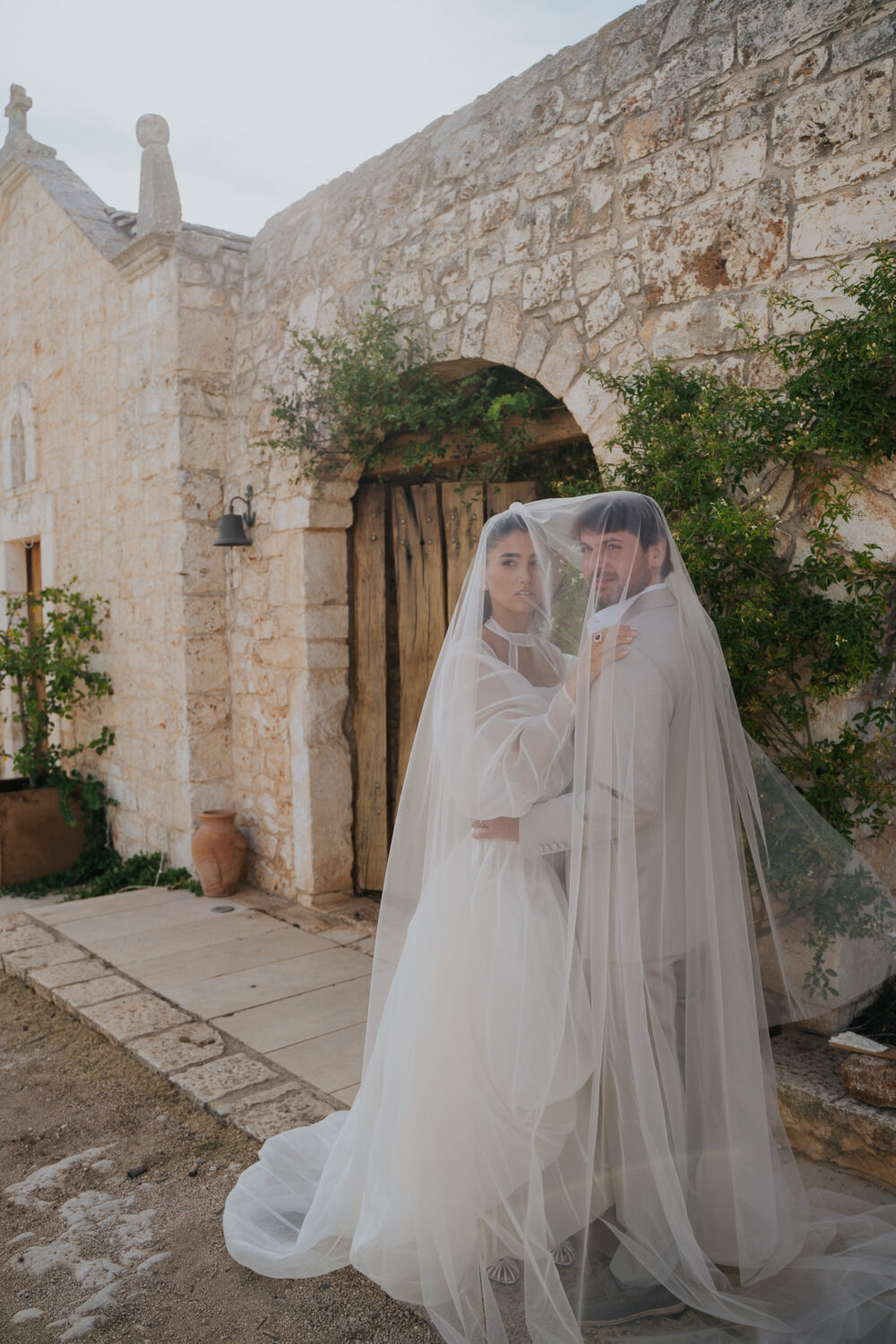 Masseria San Paolo Grande Wedding: Yasemin & Omer's Ostuni Celebration 49 Yasemin and Omer beneath their wedding veil at the estate's stone chapel