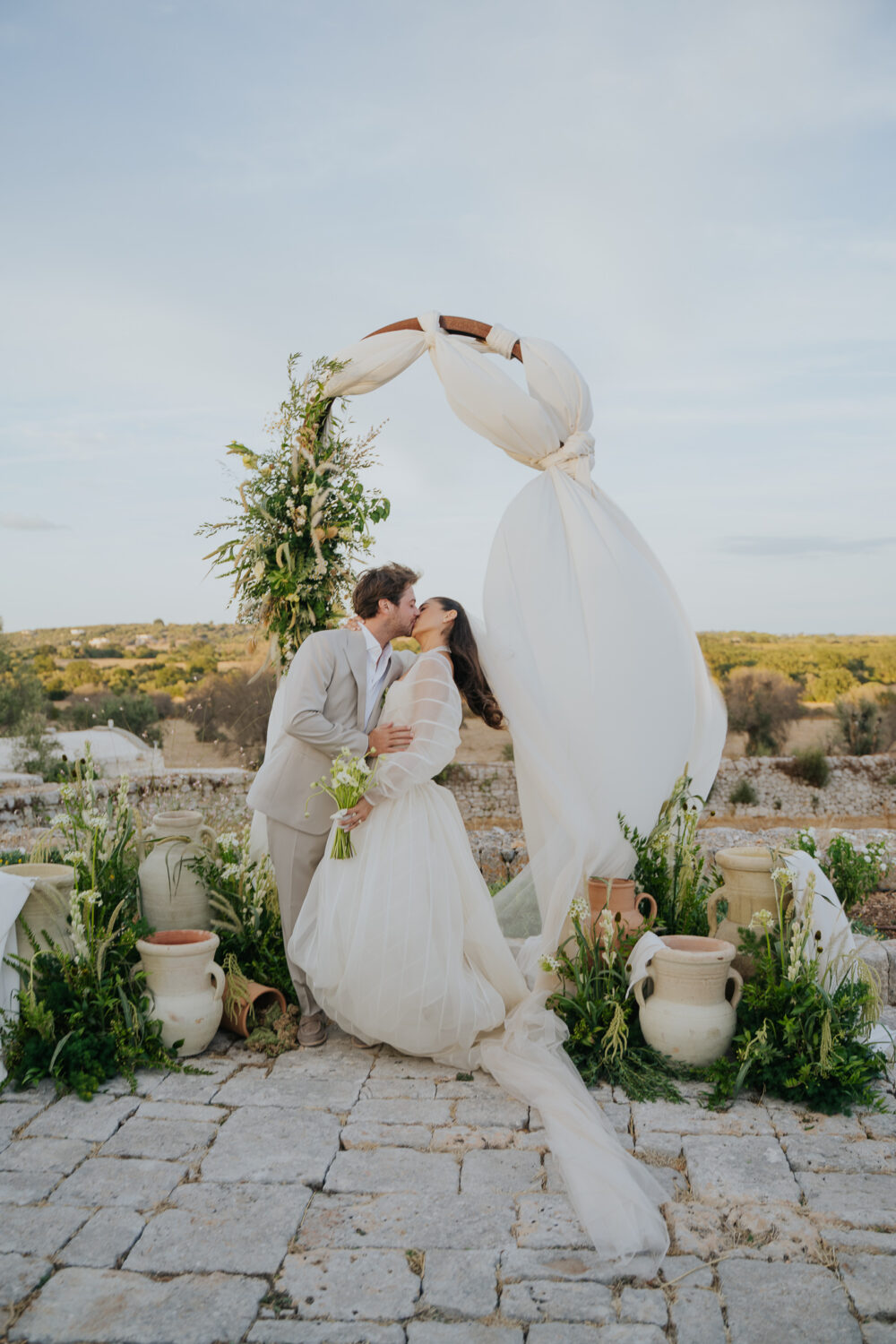 Masseria San Paolo Grande Wedding: Yasemin & Omer's Ostuni Celebration 56 Bride and groom kissing under the ceremony arch at Masseria San Paolo Grande