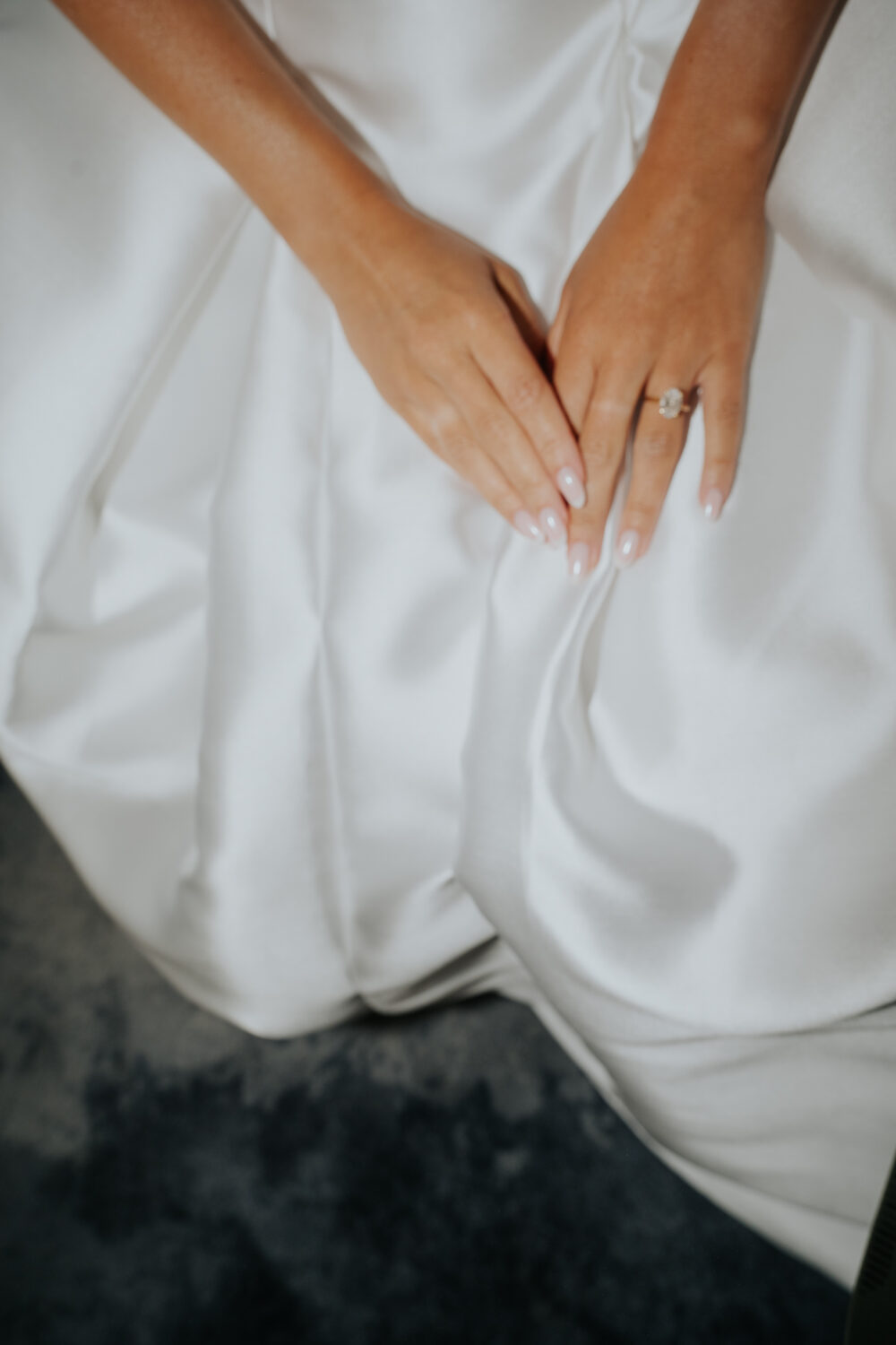 Bride putting on her ivory heeled shoe with help from a bridesmaid