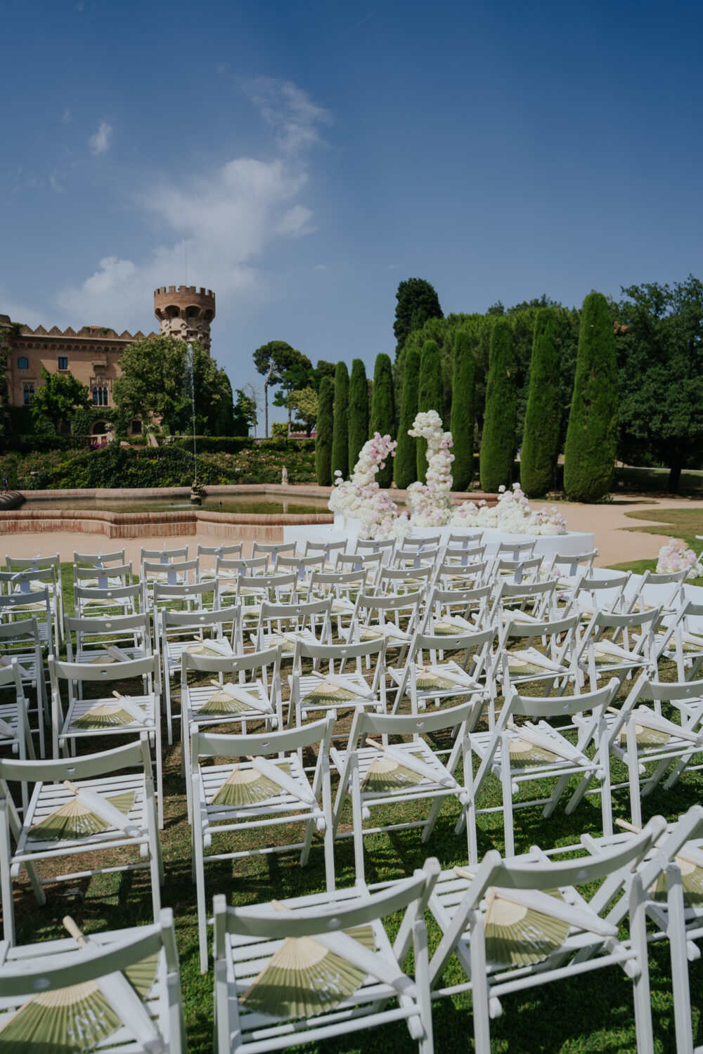 White and blush floral ceremony arch beside the fountain at Castell de Sant Marçal