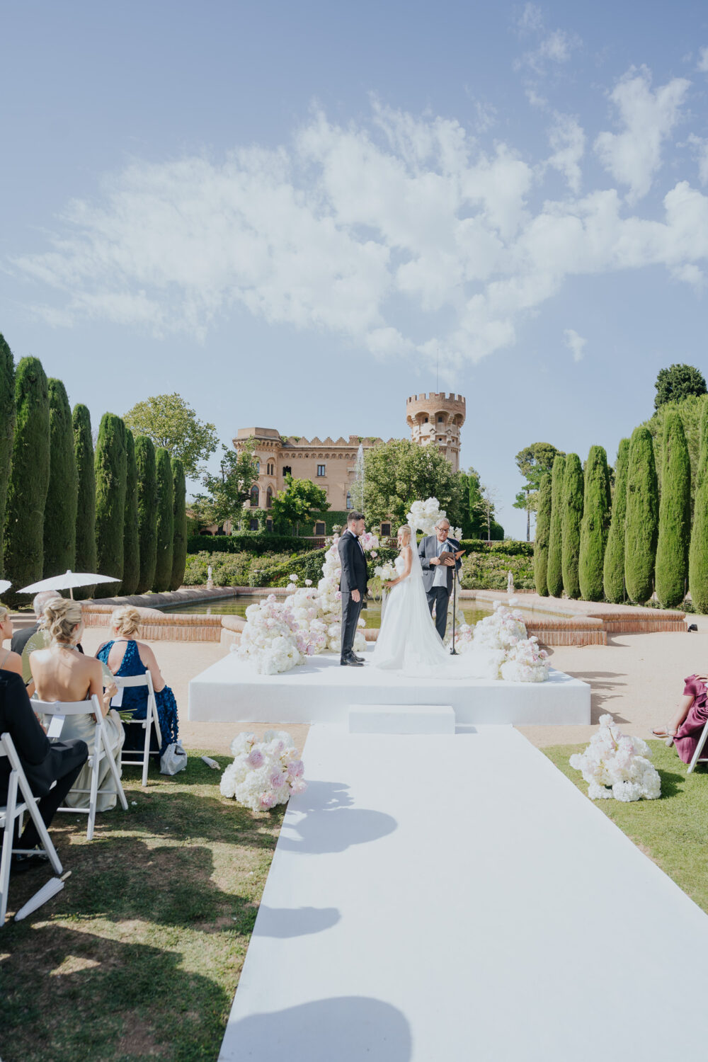 Rows of white ceremony chairs facing the floral arch and castle tower