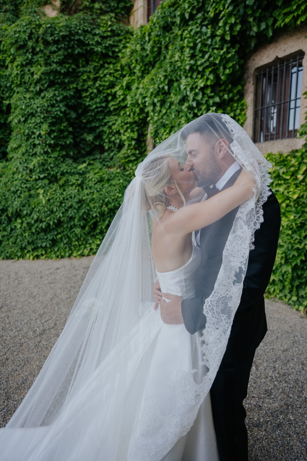 Groom and bride standing outside the ivy-covered chapel doorway at Castell de Sant Marçal