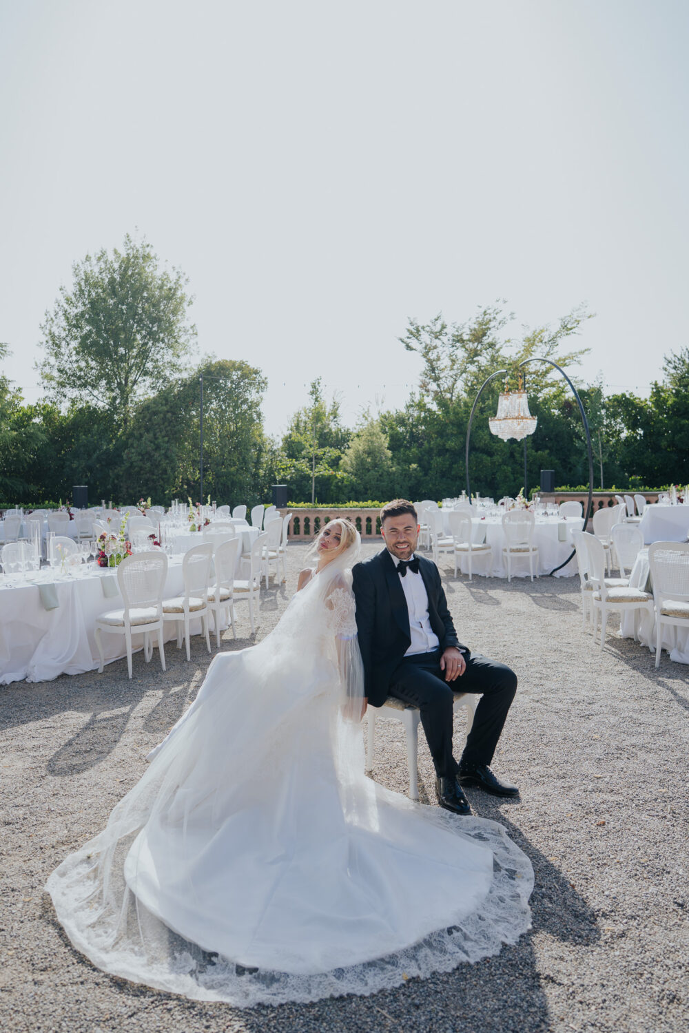 Bride and groom seated together at the reception with a chandelier arch in the background