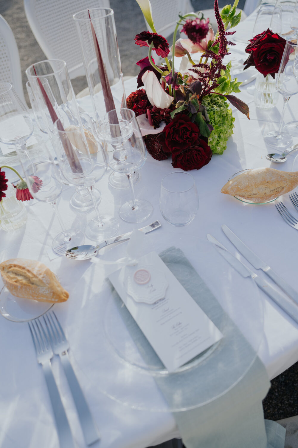 Long reception table set with white chairs and floral centerpieces at dusk