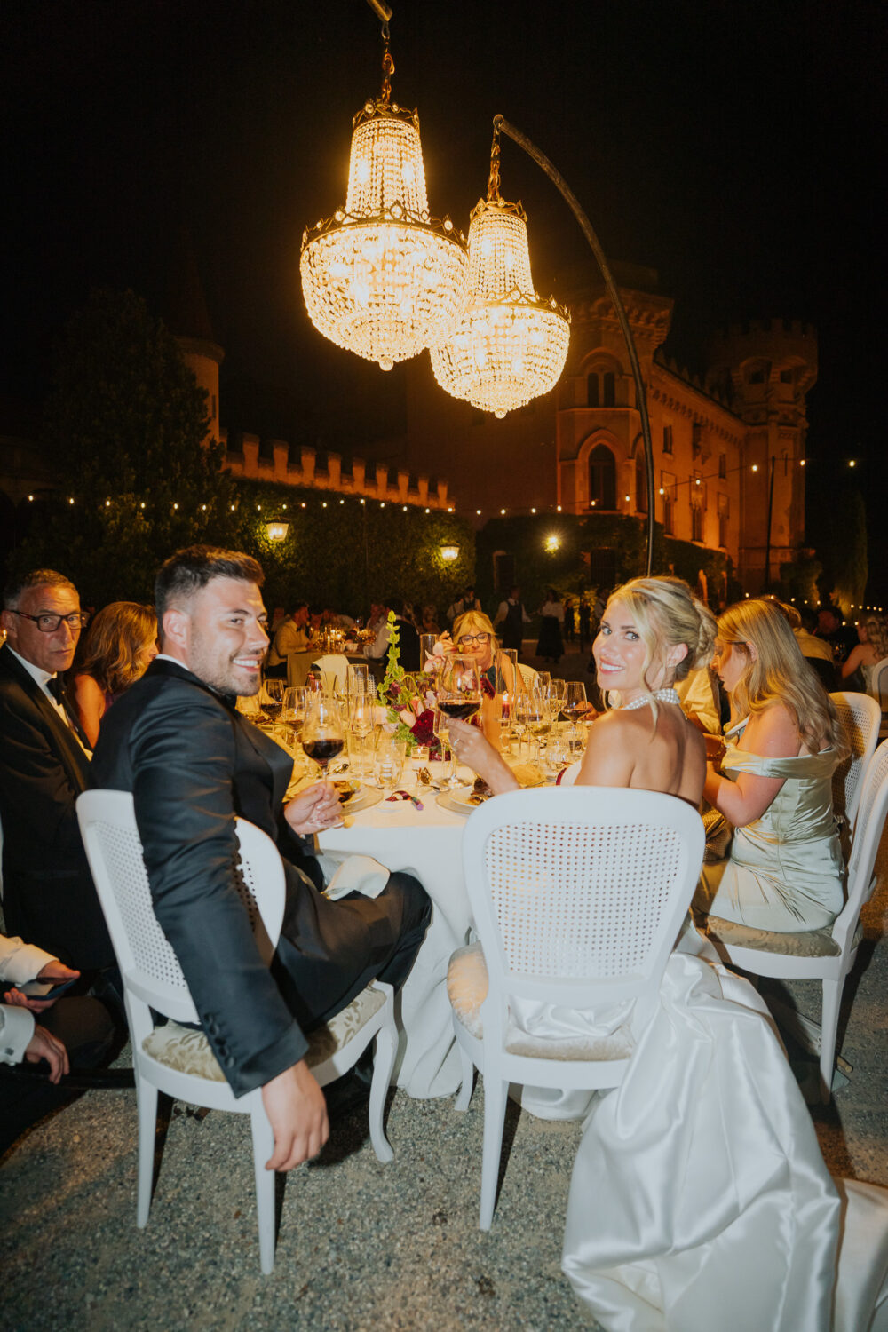 Bride and groom seated at their reception table with the castle lit up behind them
