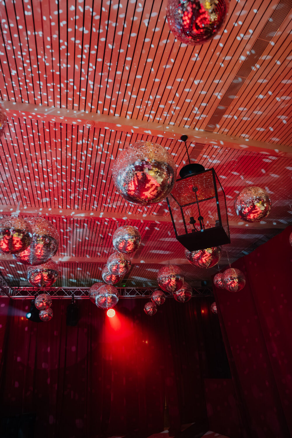 Disco balls and string lights hanging from the reception tent ceiling