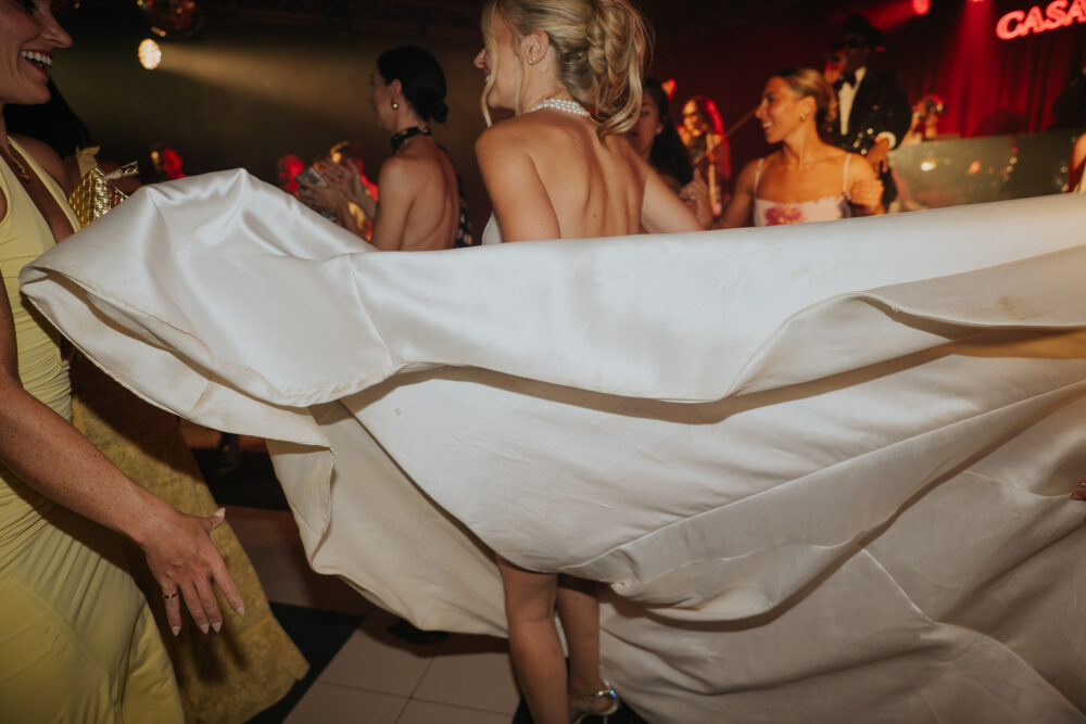 Bride's dress sweeping across the dance floor beside the Casa Shalom stage sign