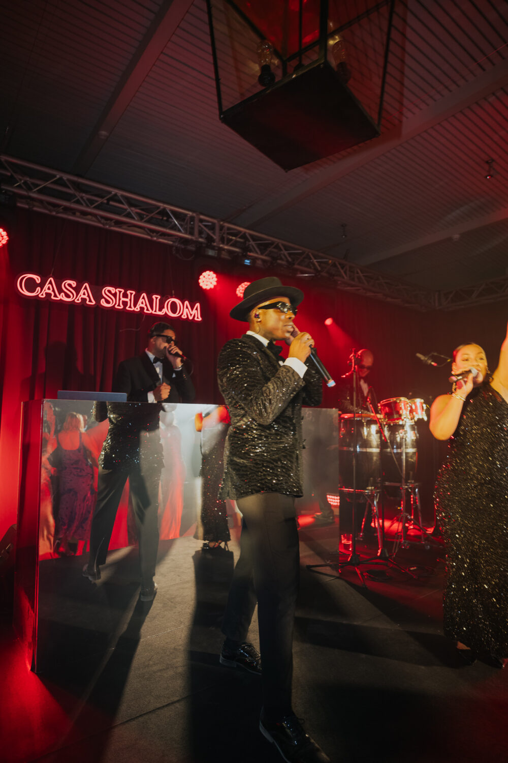 Singer performing on stage in front of the illuminated Casa Shalom sign during the party